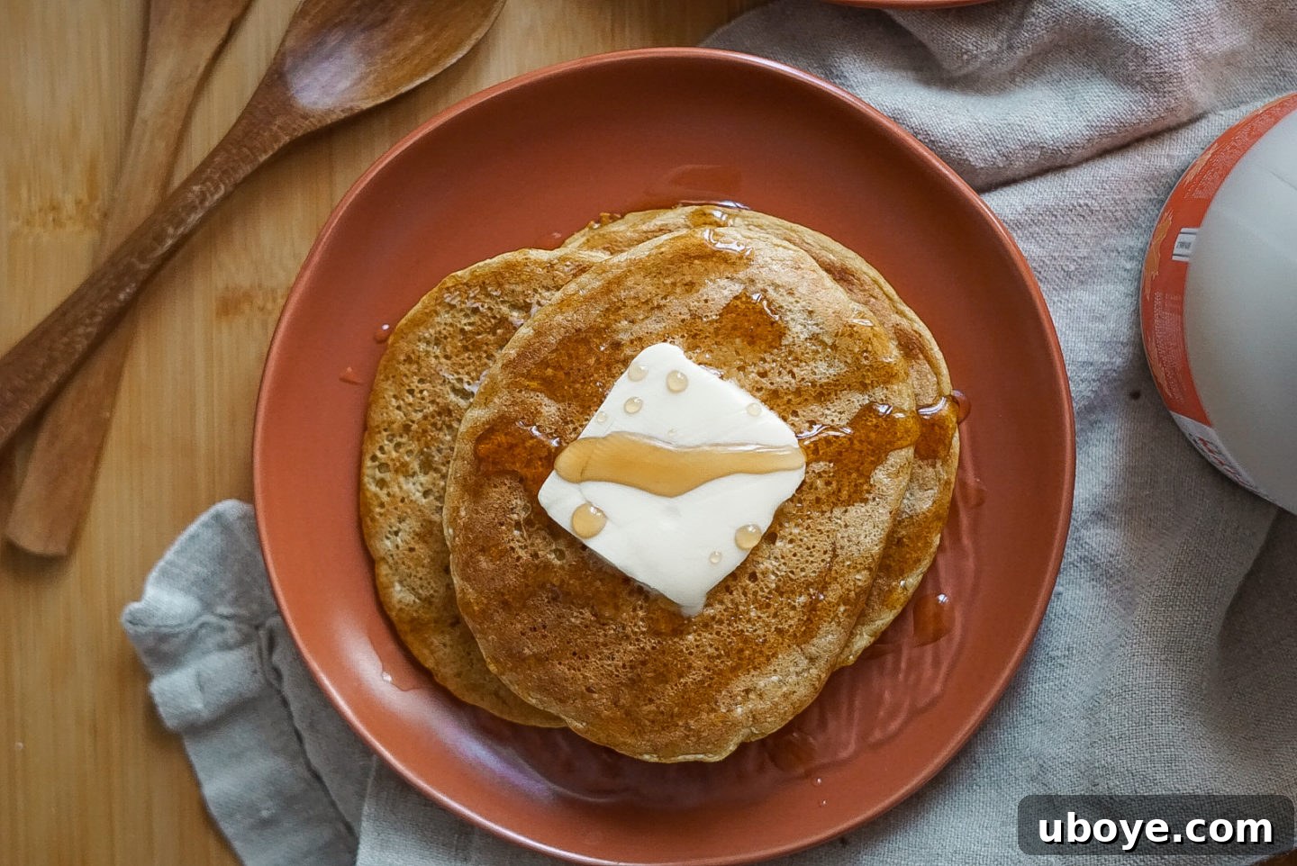 A beautifully styled shot of a stack of vegan pumpkin pancakes, garnished with a sprinkle of powdered sugar and a side of fresh berries, evoking a sense of healthy indulgence.