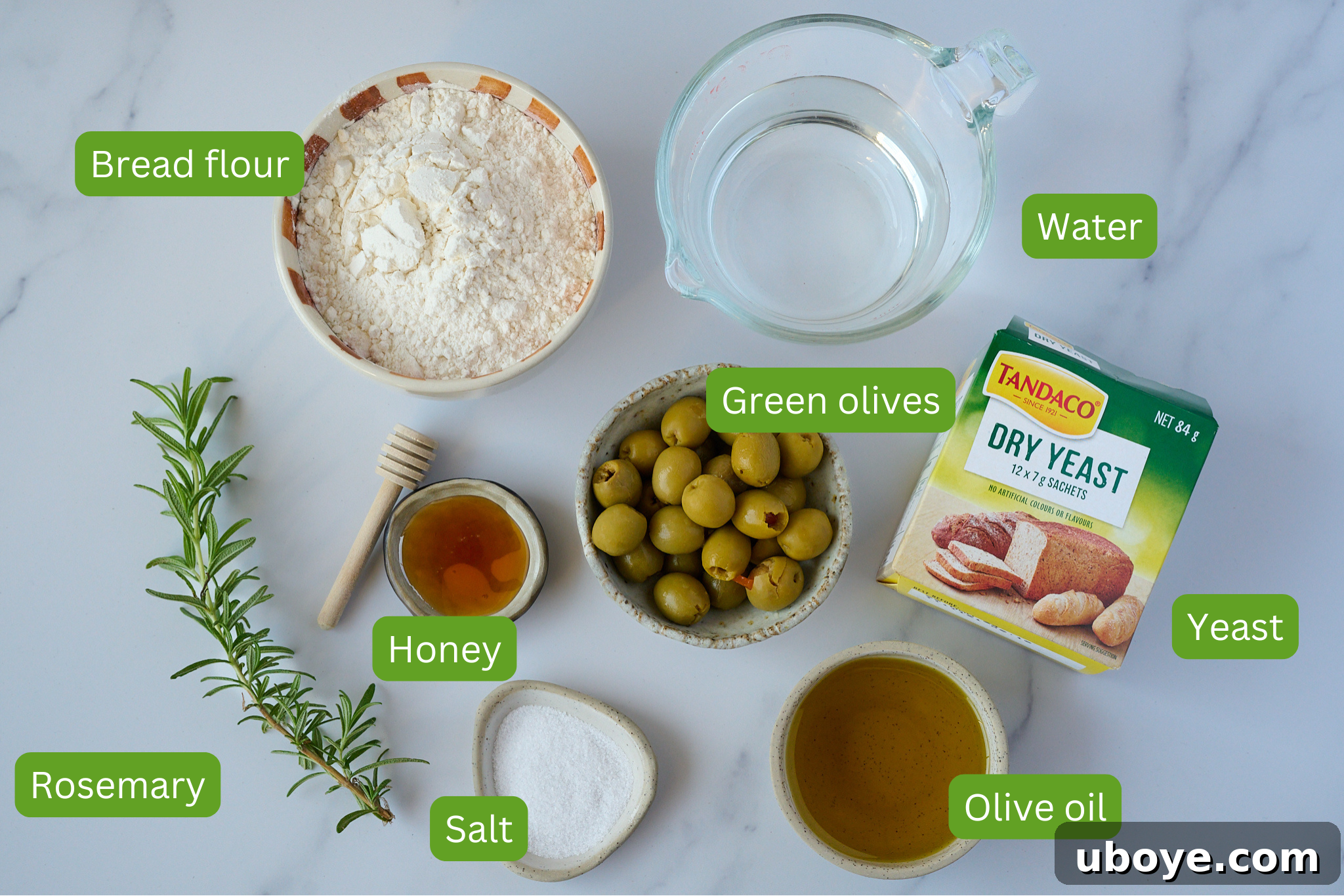 A flat lay of ingredients for focaccia: flour, olives, olive oil, yeast, salt, and rosemary.