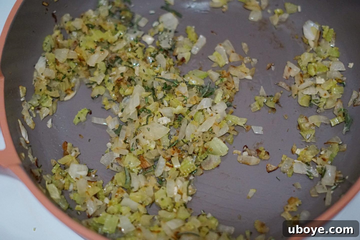Close-up of the cornbread stuffing being mixed in a bowl, with the cooked vegetables and other ingredients visible.