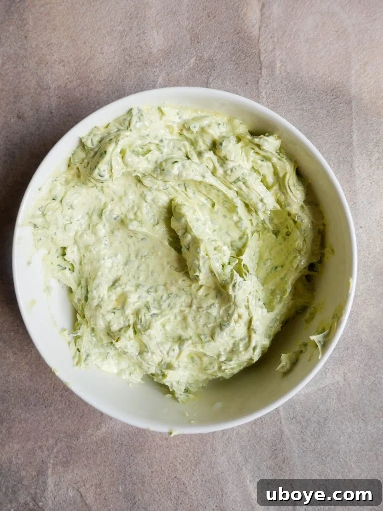 A small bowl filled with creamy, vibrant green garlic confit herb butter, showcasing its rich texture and fresh ingredients, ready to be added to dishes.