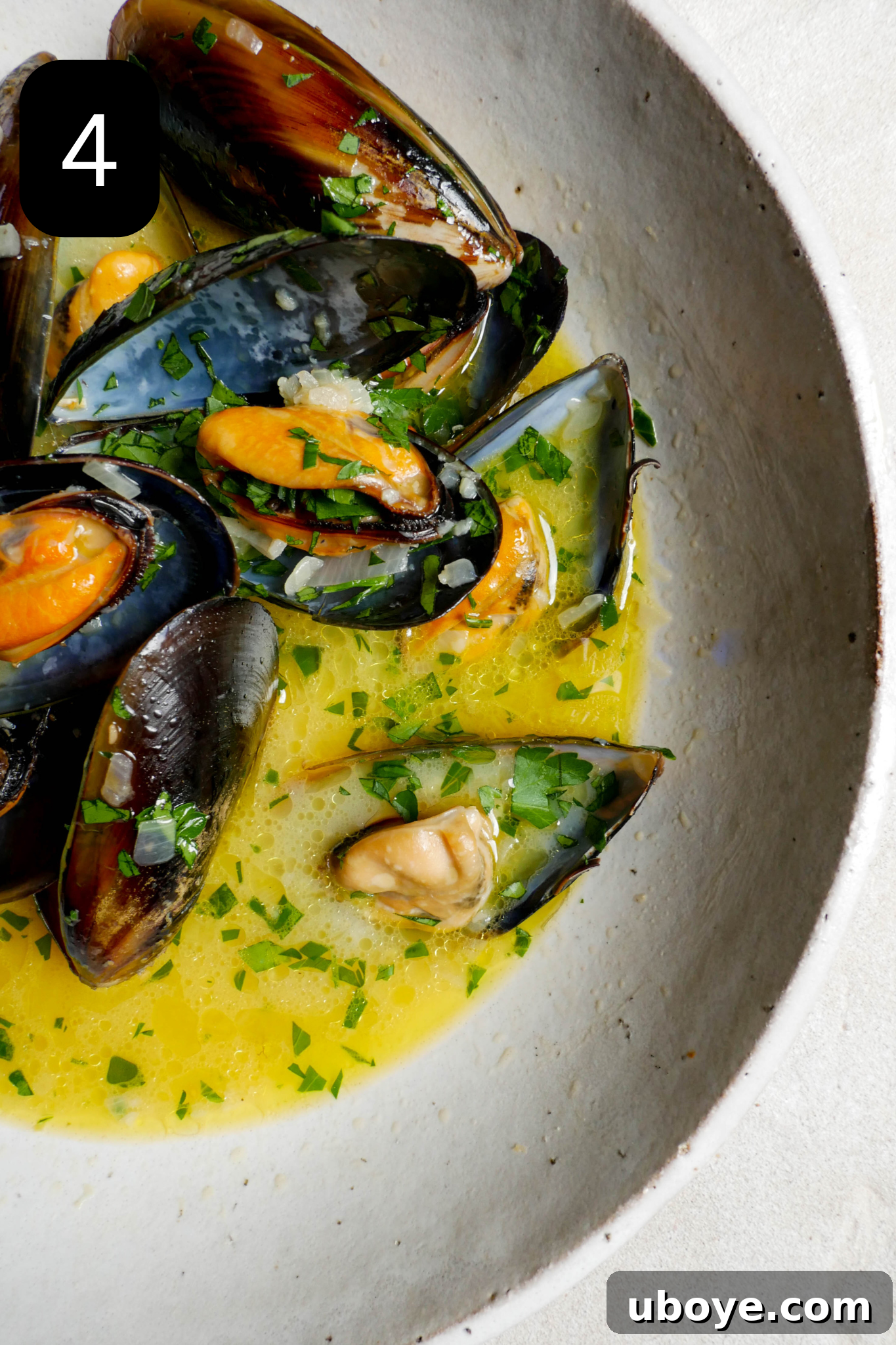 Aromatic White Wine Butter Mussels 7 Steamed white wine butter mussels served in a large white bowl, generously sprinkled with fresh green parsley, ready to be enjoyed.