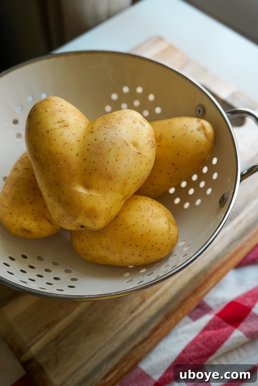 potatoes in a colander, with one heart-shaped potato visible