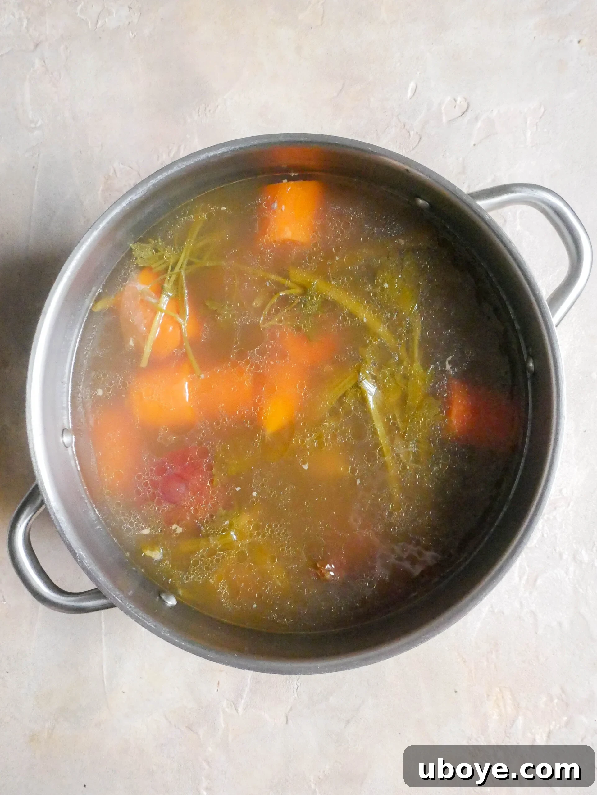 A pot of cooked chicken broth, indicating the longer simmering process.