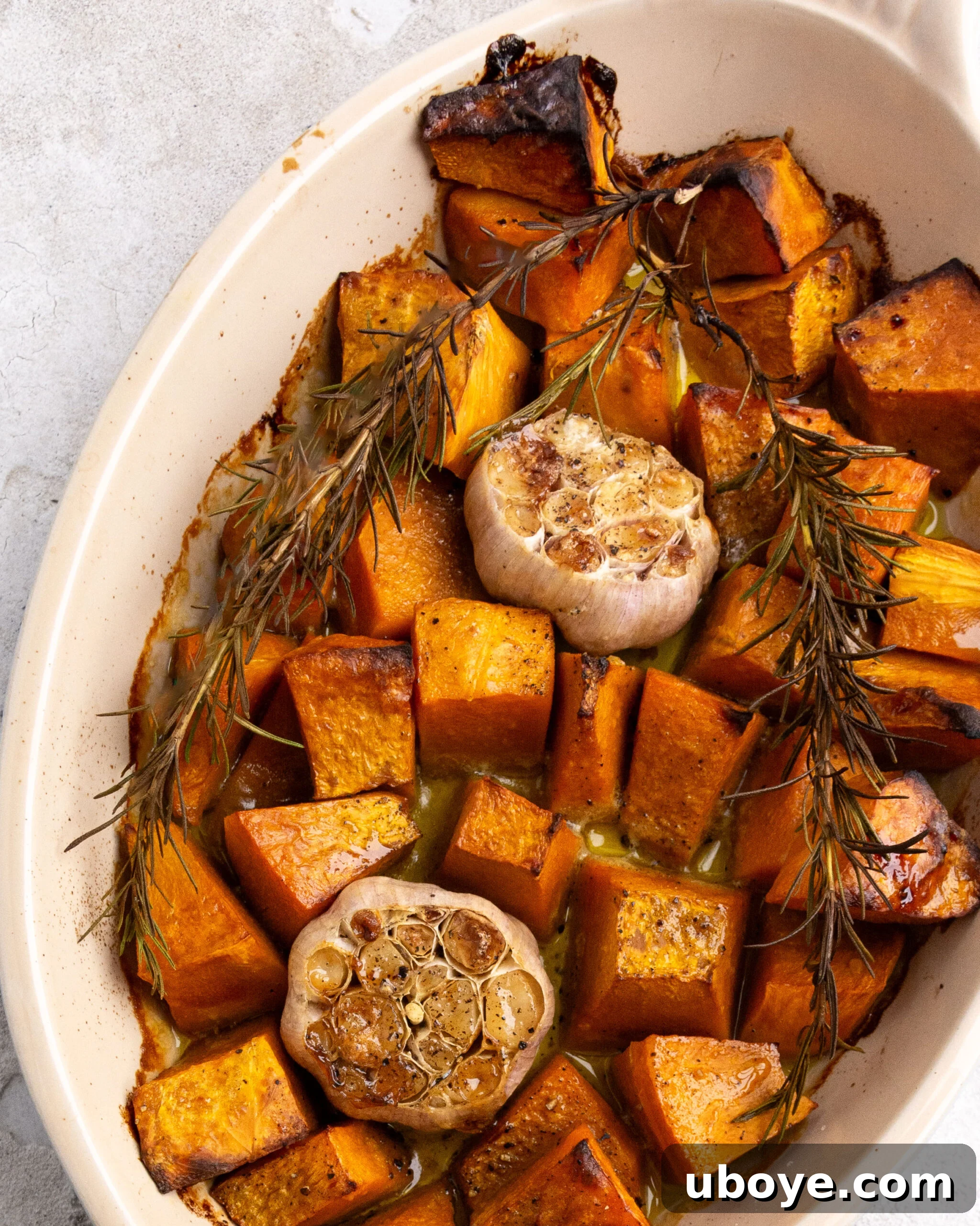 Perfectly roasted pumpkin, garlic, and rosemary resting in a baking dish, glistening and tender.