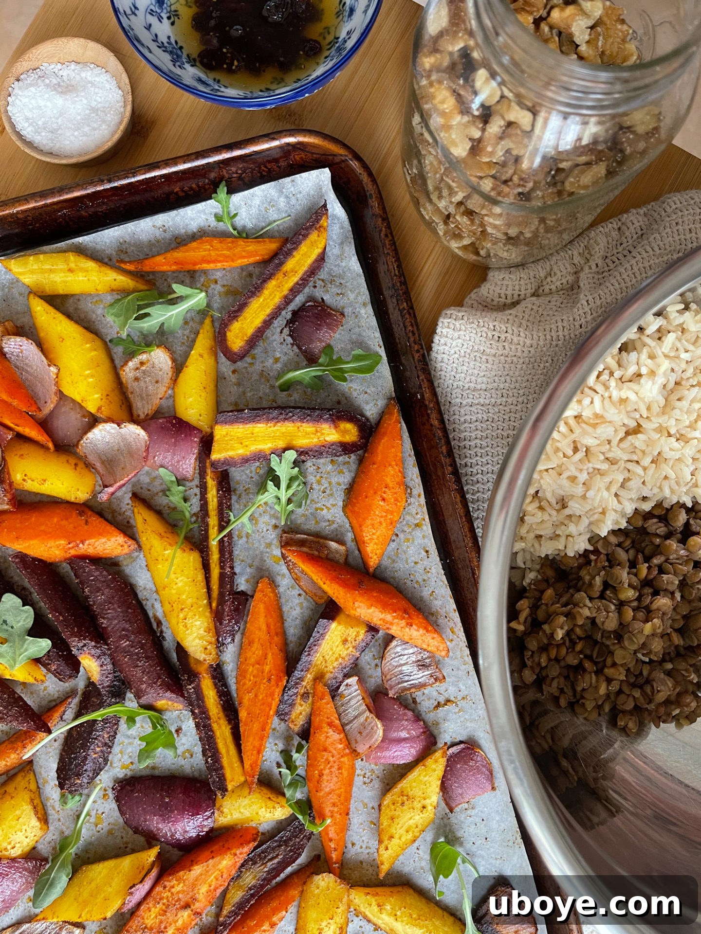 Roasted carrots and red onions coated with aromatic spices on a baking sheet, ready for the oven