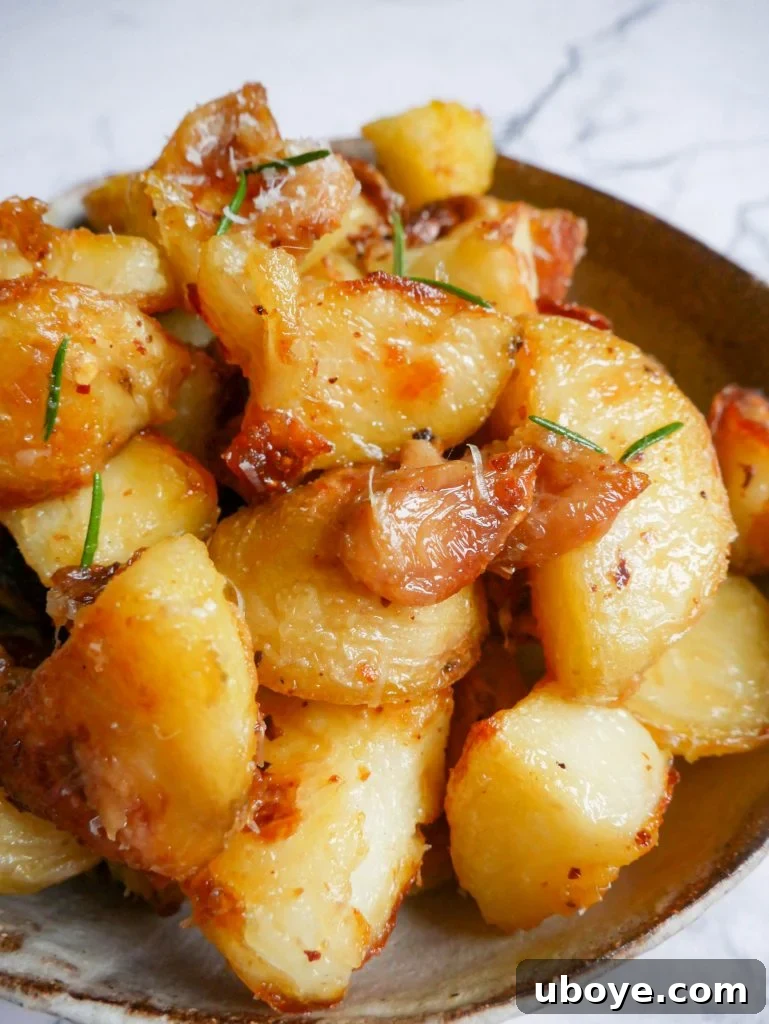 Large serving of garlic confit crispy roasted potatoes in a pan, garnished with fresh rosemary