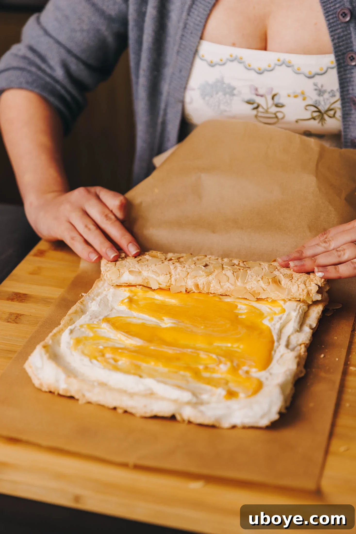 You can see baking paper and two hands rolling roulade. 