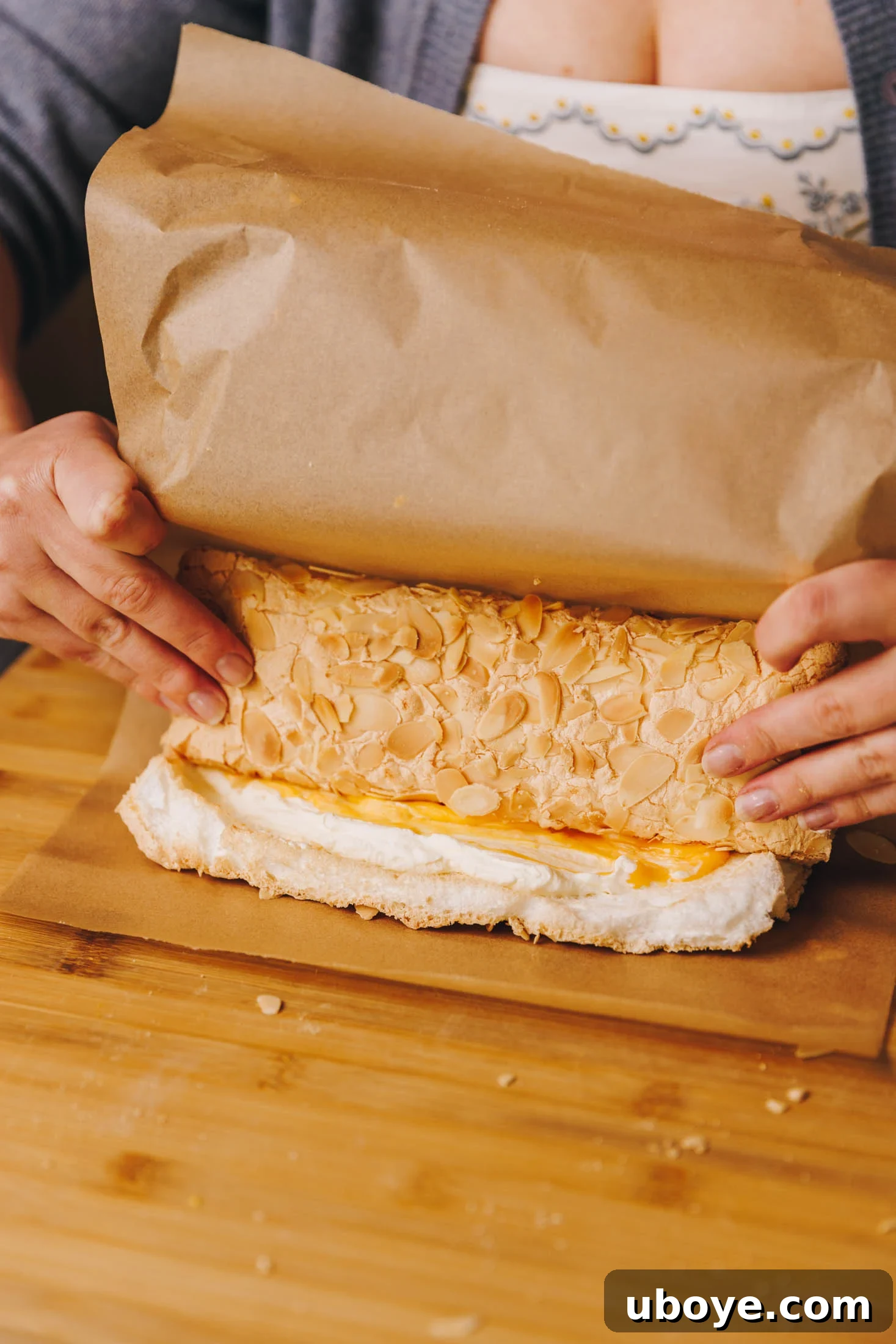 You can see baking paper and two hands rolling roulade. 