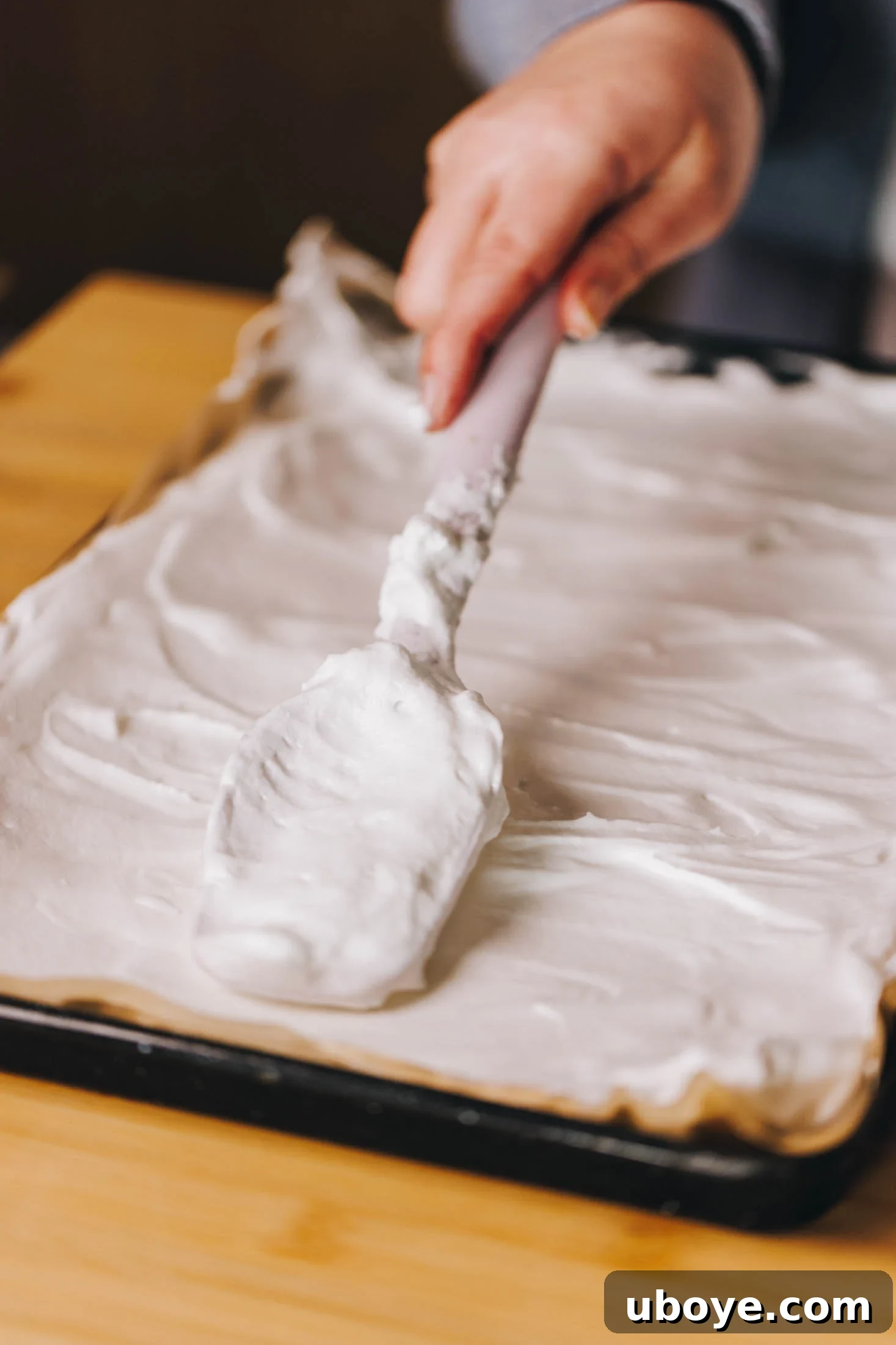 Meringue is being spread onto prelined baking tray.