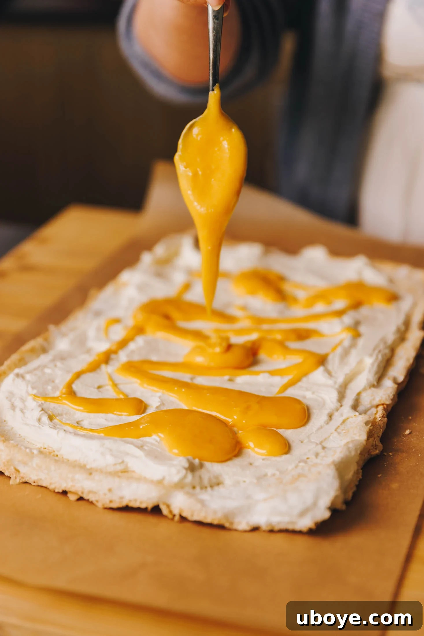 Lemon curd is being drizzled onto meringue