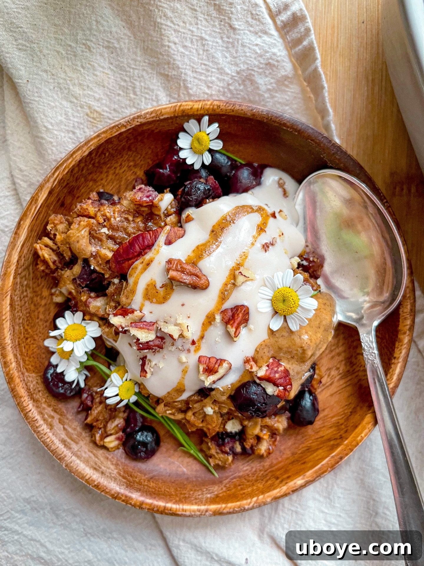 A close-up shot of a single serving of blueberry breakfast crumble in a small dish, topped with a dollop of vegan yogurt and a drizzle of almond butter.