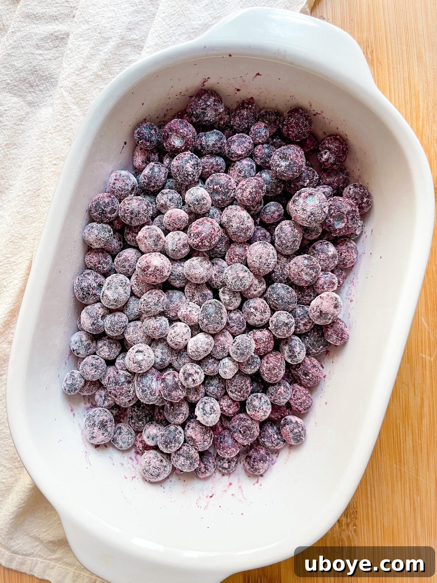 A baking dish filled with the lightened up blueberry breakfast crumble, showing the golden brown oat topping and bubbling blueberry filling.