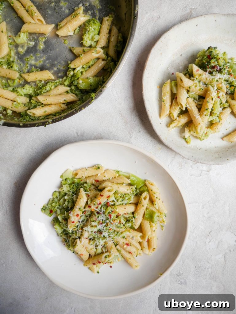Velvety Broccoli Cheddar Pasta 4 Ingredients for cheesy broccoli pasta laid out on a wooden board, including broccoli, pasta, garlic, and cheese.