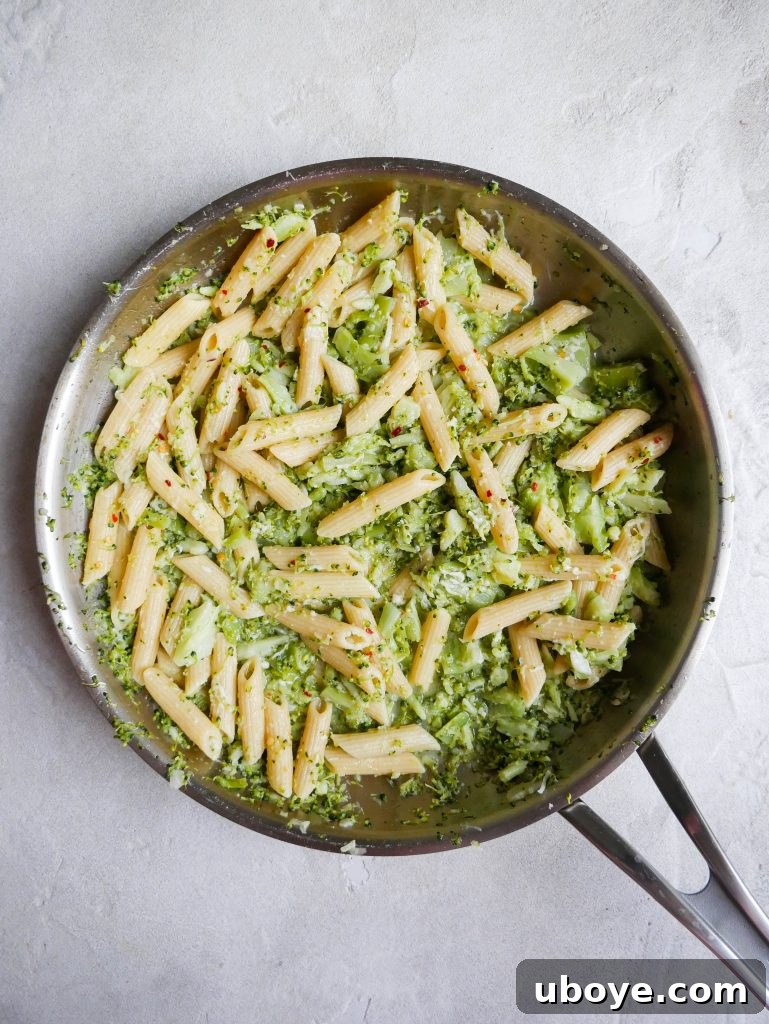 Velvety Broccoli Cheddar Pasta 5 A close-up shot of the creamy cheesy broccoli pasta being stirred in a large pan, showing the rich texture.