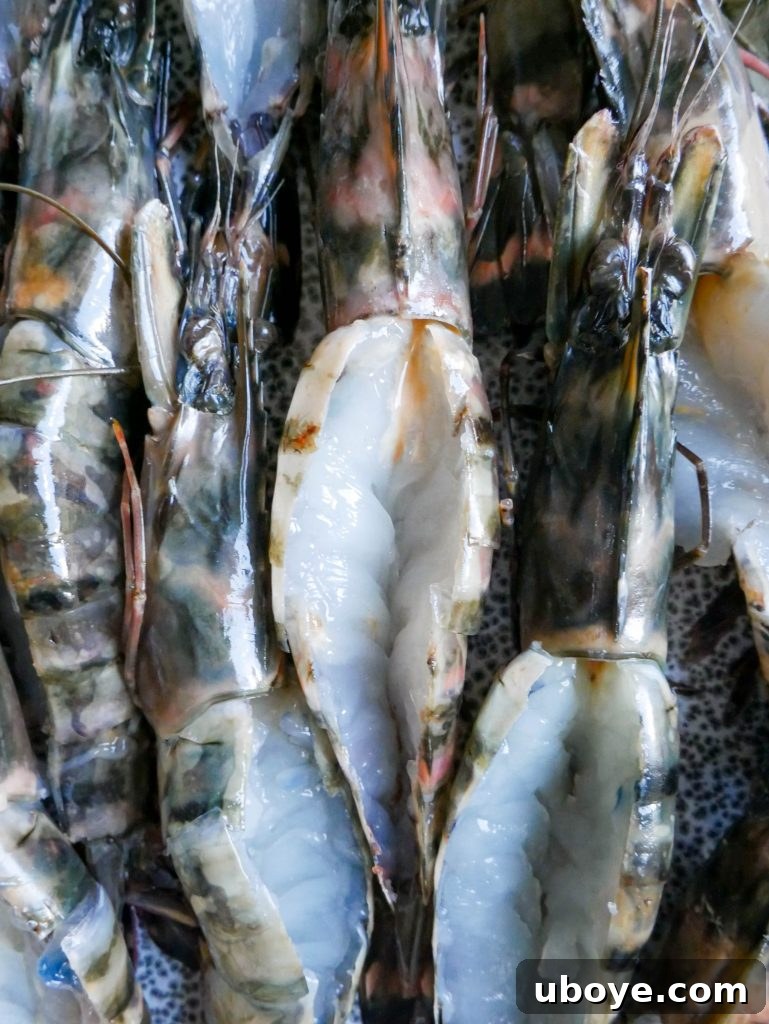 Chef's hands butterflying prawns, demonstrating the technique