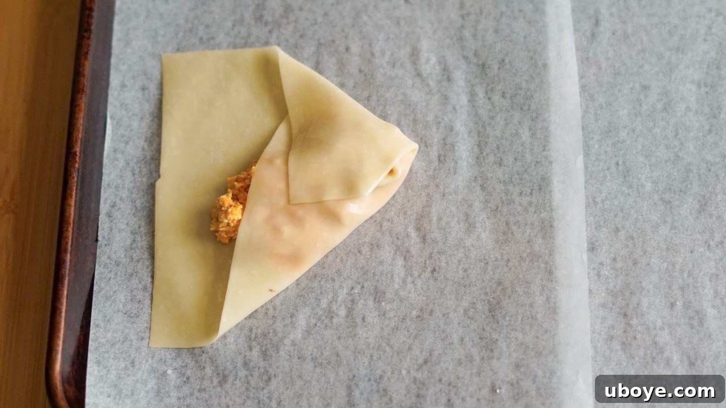 Folding an eggroll wrapper with vegan buffalo chicken filling