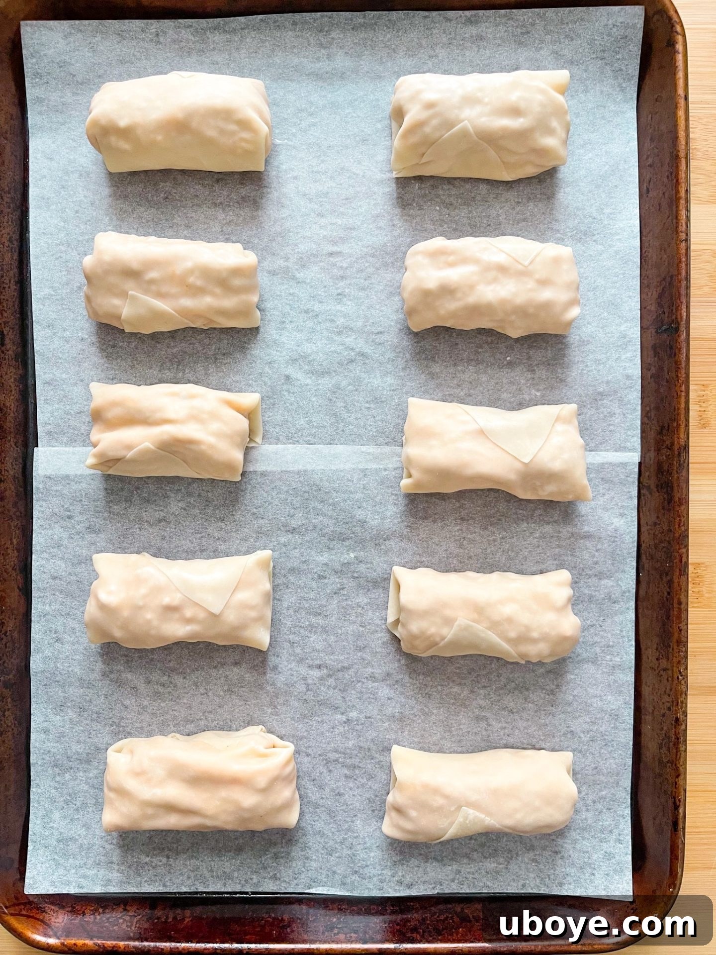 Baked vegan buffalo chicken eggrolls on a baking sheet, golden and crispy