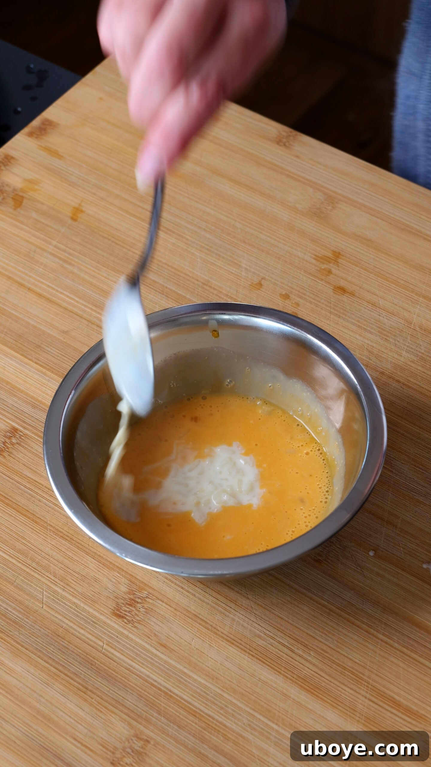 Abuelo's Arroz con Leche Spanish Rice Pudding 5 Whisked egg yolks in a small bowl, with a spoonful of warm, cooked rice pudding being slowly added to temper them.