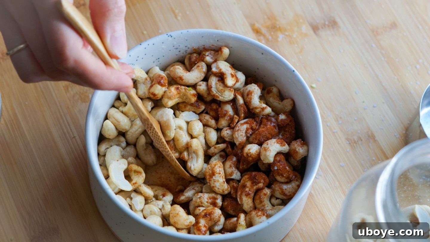 Mixing the chili lime seasoning with raw cashews in a bowl for an oil-free vegan snack.