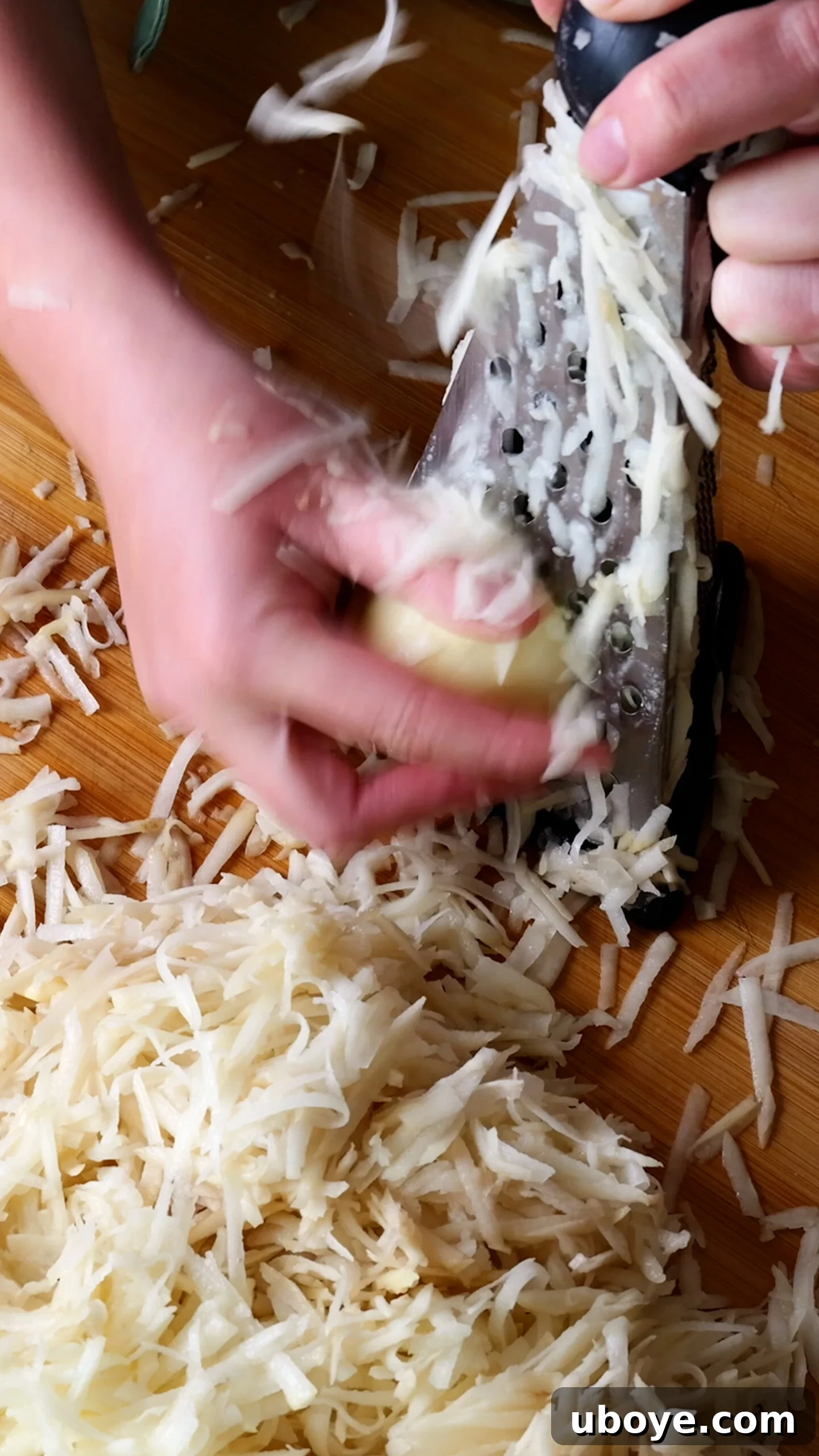 Golden Crispy Potato Rosti 4 Raw potato being grated using the coarse side of a cheese grater over a cutting board.