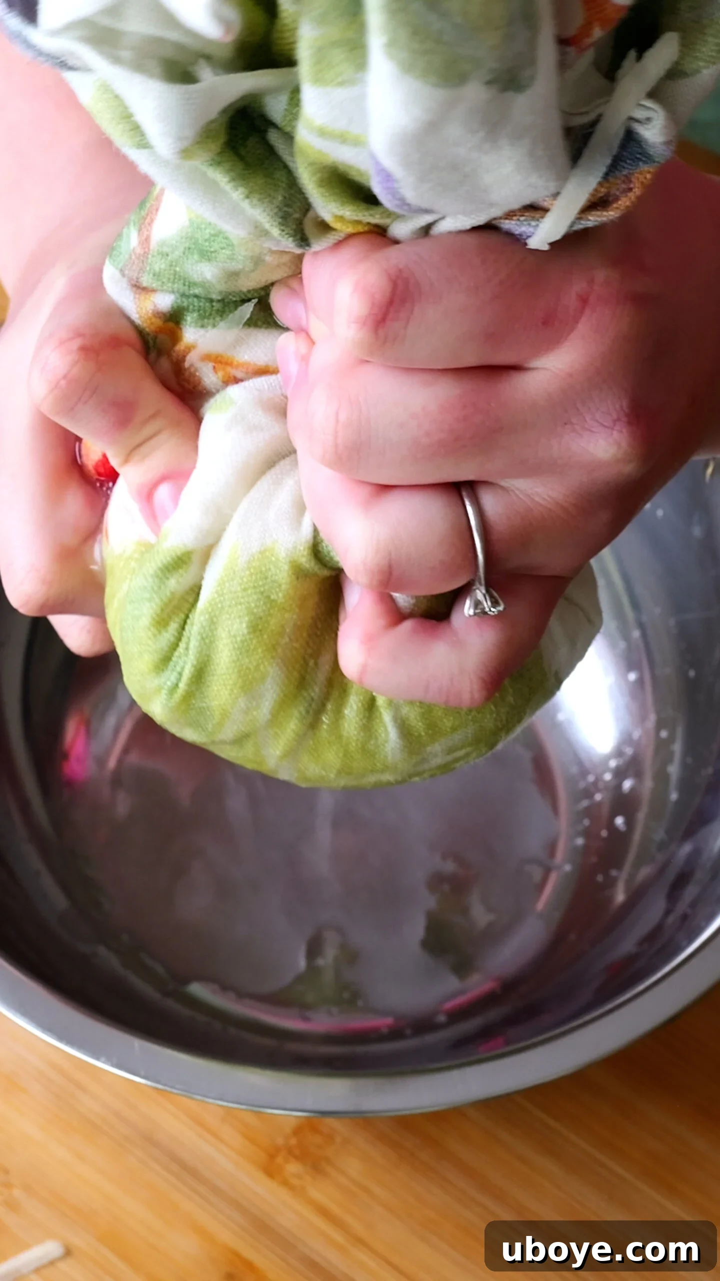 Golden Crispy Potato Rosti 7 Grated potatoes wrapped in a green tea towel, being vigorously squeezed to extract excess water into a metal bowl.