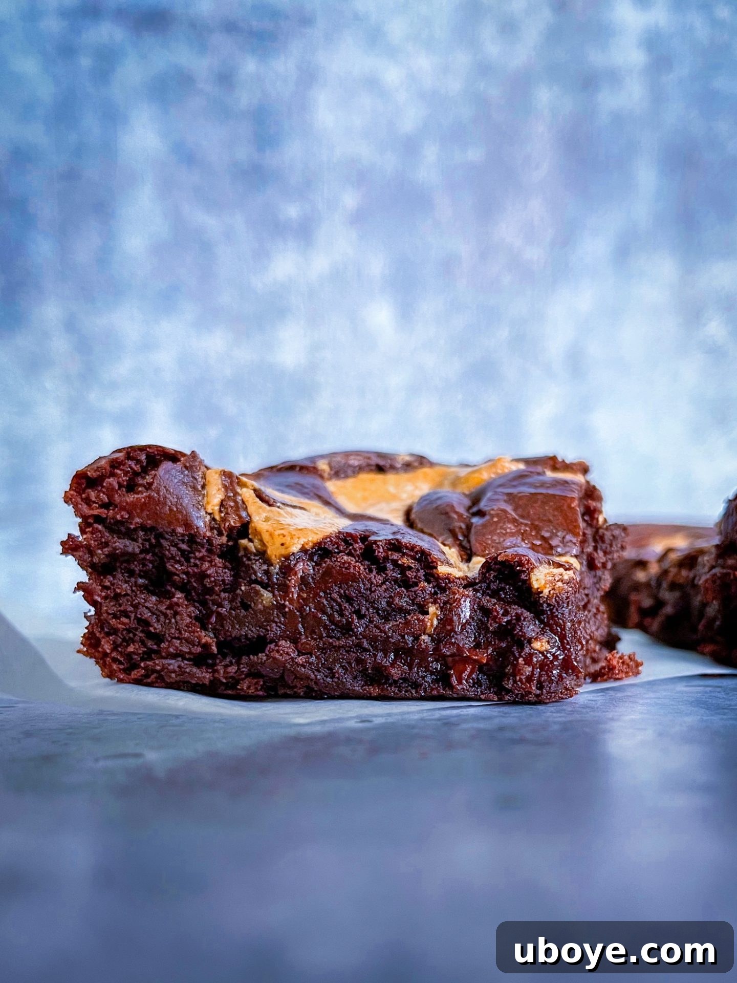 Close-up view of a rich, fudgy vegan brownie square, showcasing its gooey texture and crinkly top