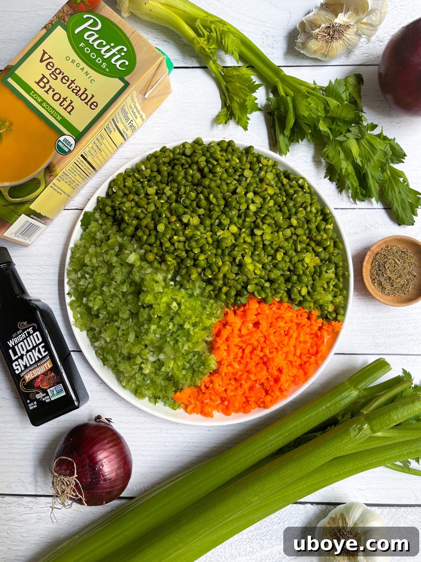 A selection of fresh ingredients including split peas, carrots, celery, onion, and garlic for making vegan split pea soup.