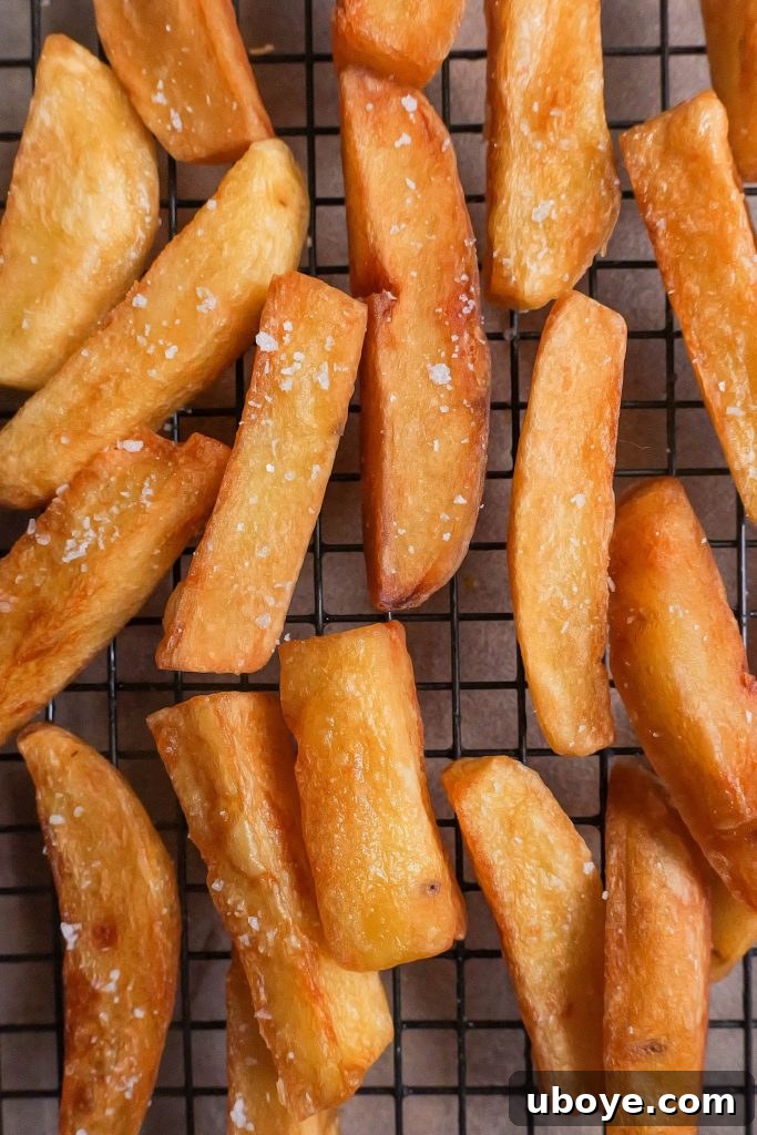 Uncooked, hand-cut russet potatoes, ready for the triple-cooking process to become crispy chips.
