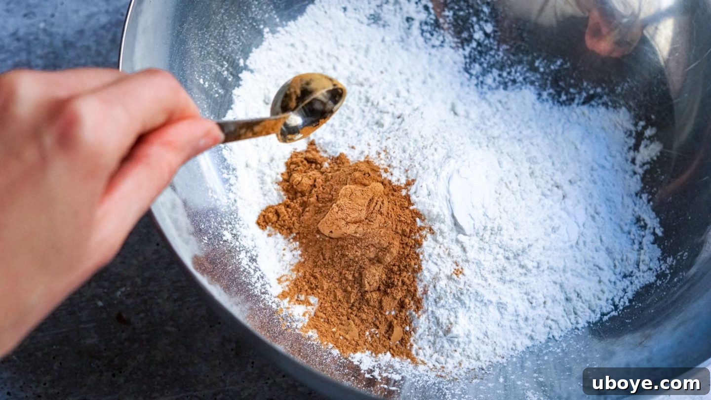 Decadent Vegan Gingerbread Cake 4 Adding cinnamon to a bowl of dry ingredients