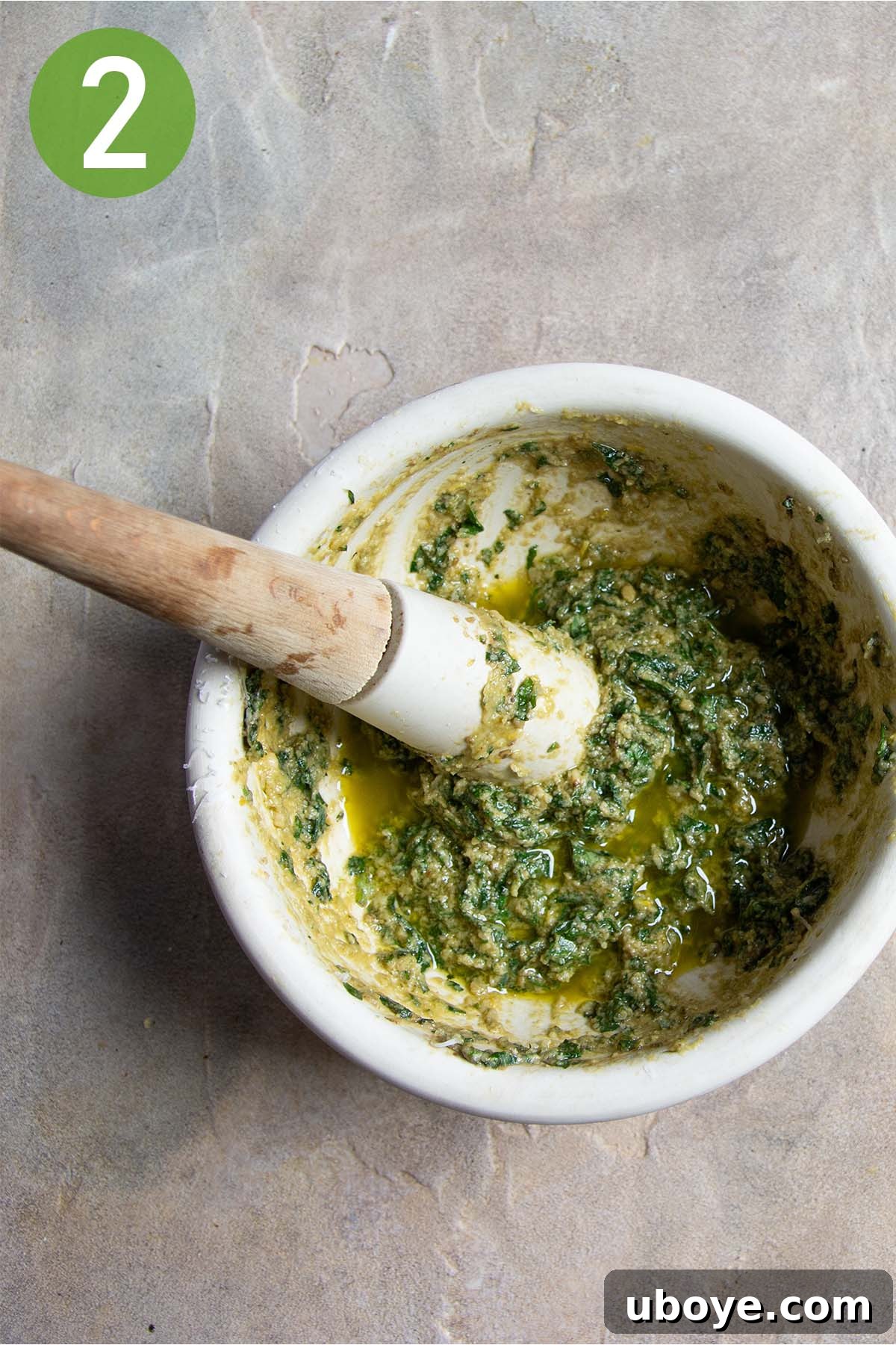 Velvet Garlic Pesto Pasta 5 Fresh basil leaves, pine nuts, and garlic confit being mashed in a traditional mortar and pestle to create homemade pesto.