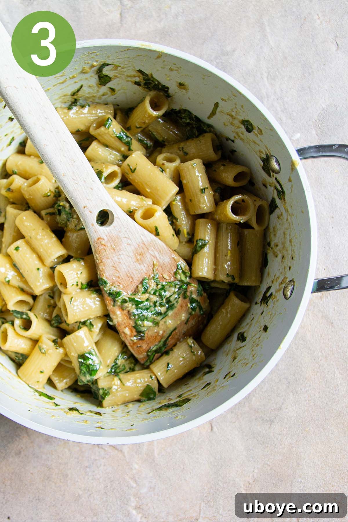 Velvet Garlic Pesto Pasta 6 Al dente pasta tossed with vibrant green pesto in a large Dutch oven with a wooden spoon.