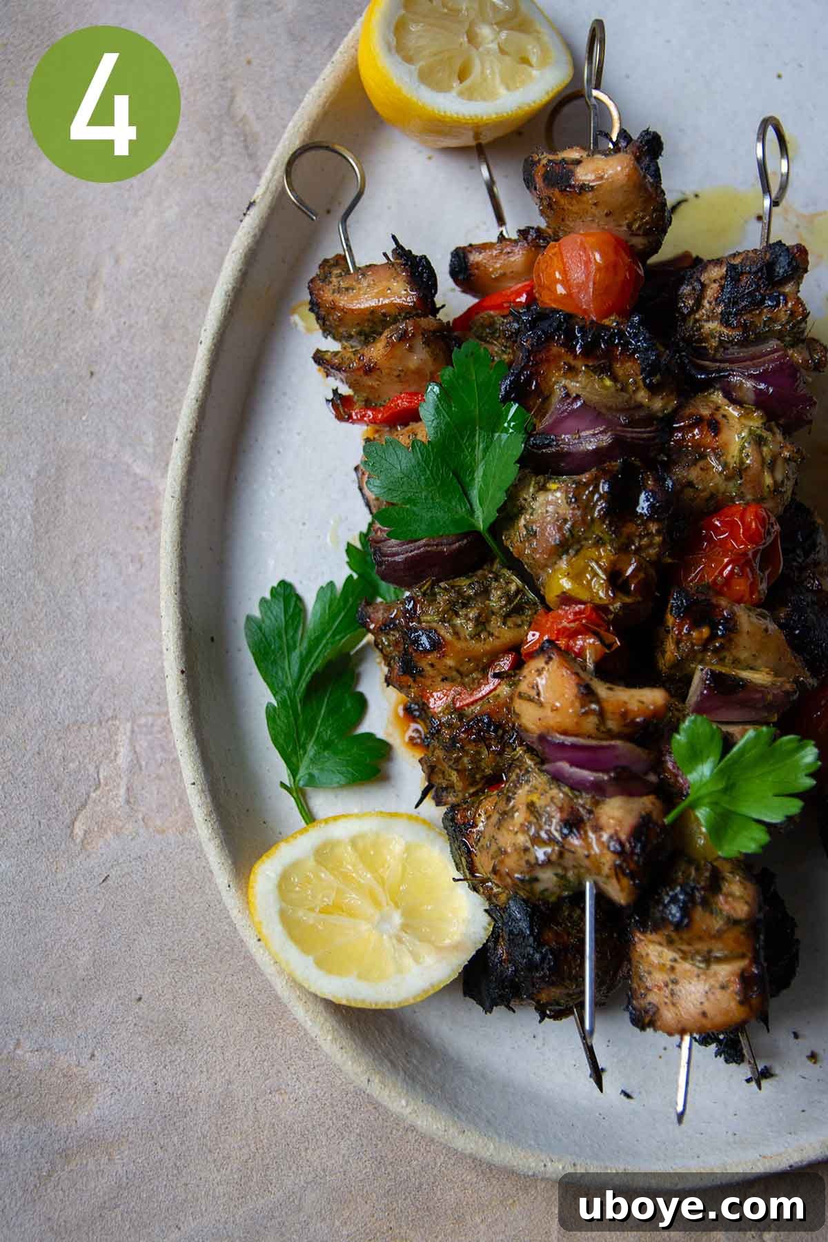 Grilled chicken skewers with parsley and lemon wedges on a serving platter.