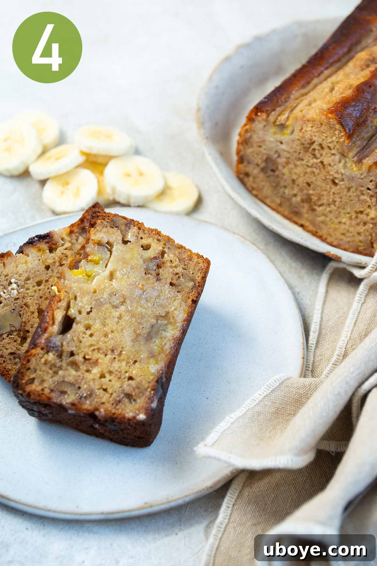 A delectable slice of olive oil banana bread on a white plate with a napkin, ready to be savored.