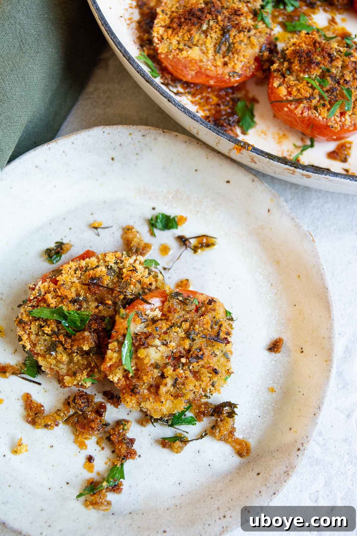 Sun-Kissed Roasted Tomatoes with Garlic-Herb Crumble 8 two stuffed tomatoes on a white plate with a green napkin.