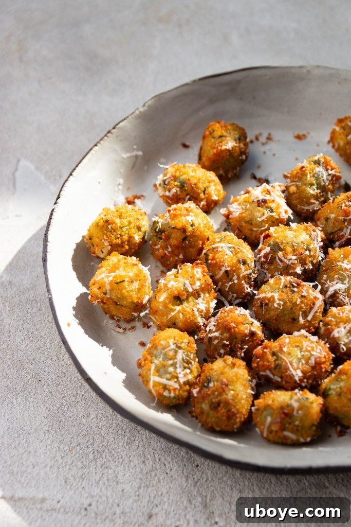 Slotted spoon carefully lowering breaded olives into hot oil