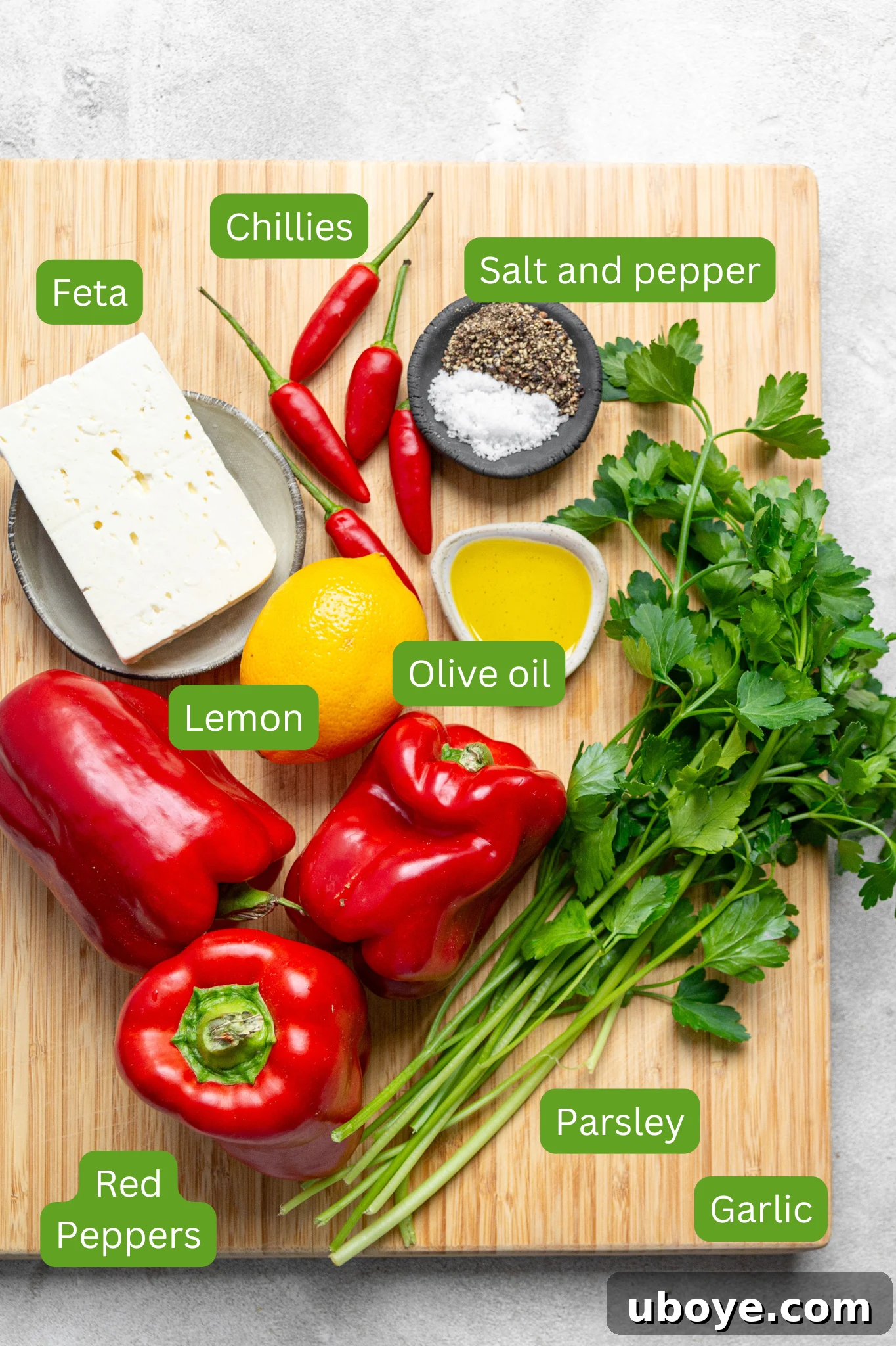 Fiery Feta and Red Pepper Dip 3 A selection of fresh ingredients laid out, including parsley, garlic bulbs, vibrant red bell peppers, a lemon, olive oil, a block of feta cheese, and salt and pepper. All components for the red pepper feta dip.