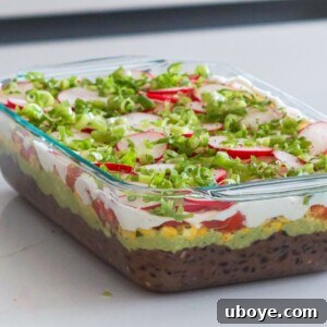 vegan seven layer dip in a glass casserole dish on a white counter