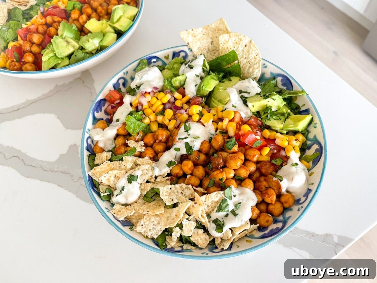 Fiesta Chickpea Taco Salad 3 Two plates of colorful vegan taco salad on a pristine white counter, beautifully showcasing the fresh ingredients, vibrant presentation, and appealing textures.