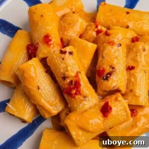 blue and white striped plate of tomato garlic confit pasta.