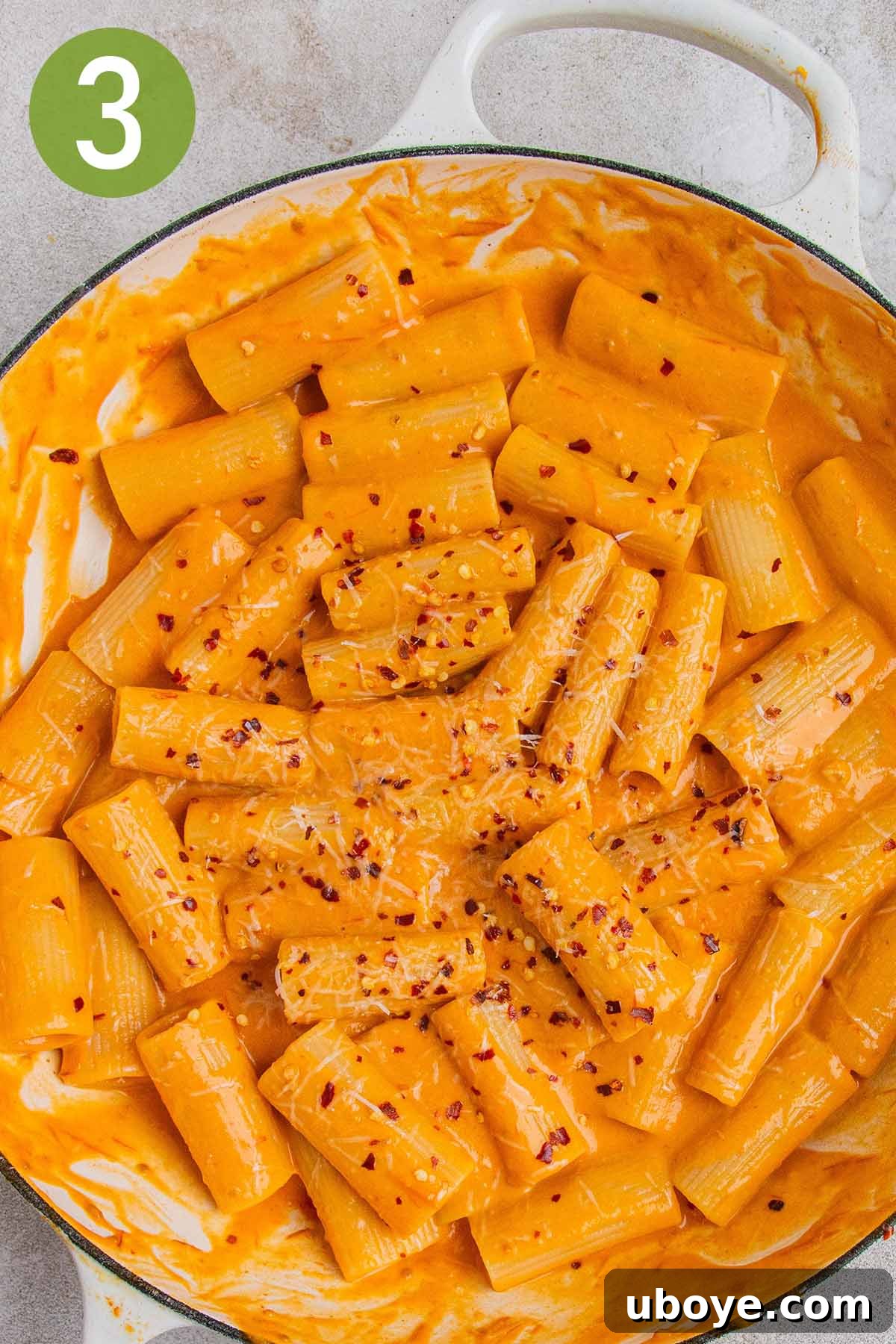 Golden Garlic Tomato Pasta 6 Pot of tomato garlic confit pasta with grated cheese and chili flakes, being stirred gently.