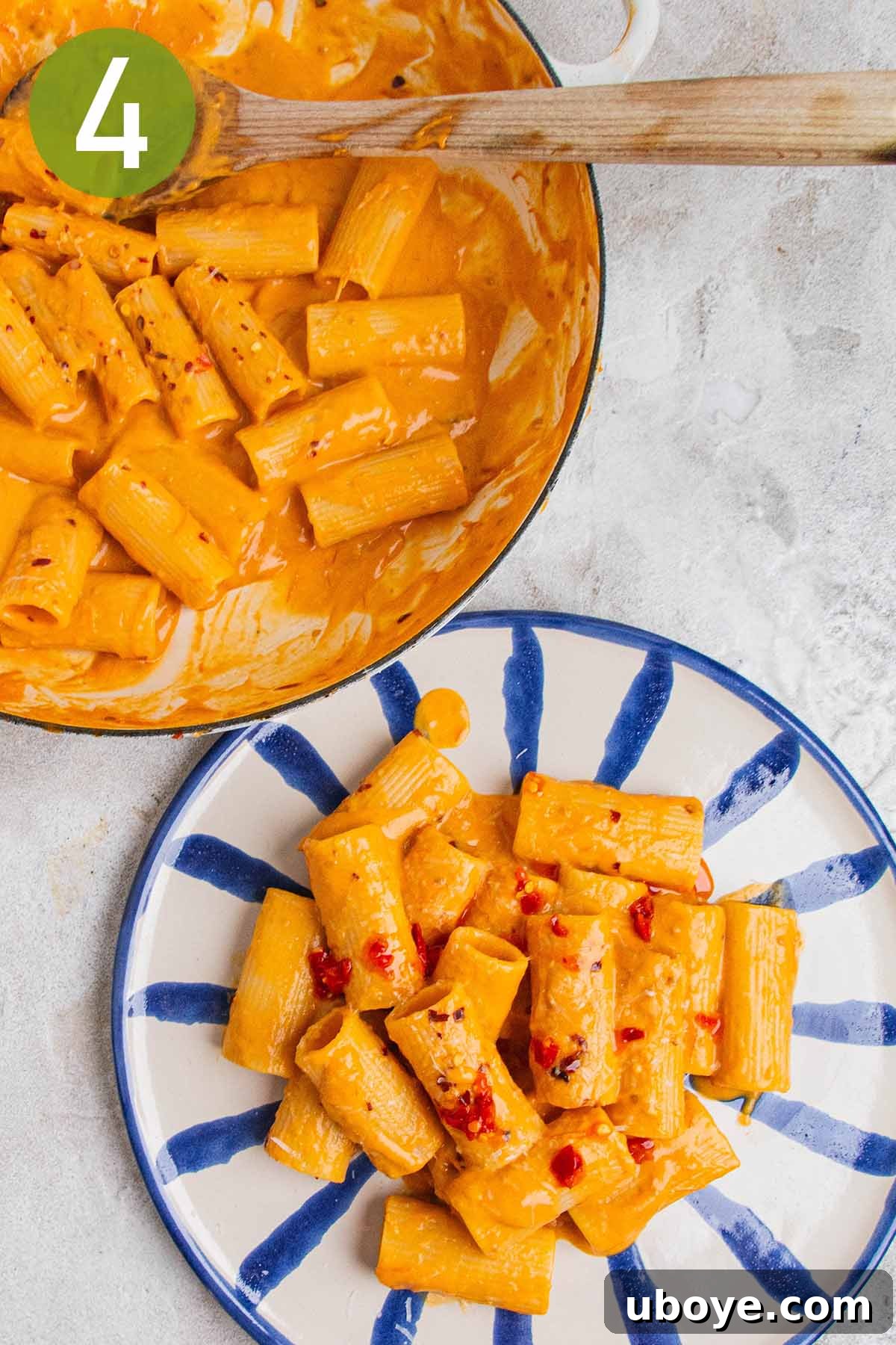 Golden Garlic Tomato Pasta 7 Serving a portion of tomato garlic confit pasta with a wooden spoon onto a bowl, showing the creamy texture.