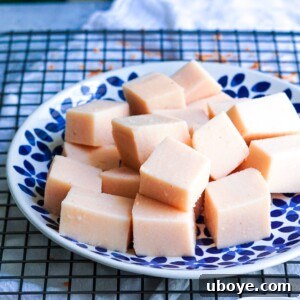 A delicious block of homemade red lentil tofu on a rustic wooden board, ready for preparation.