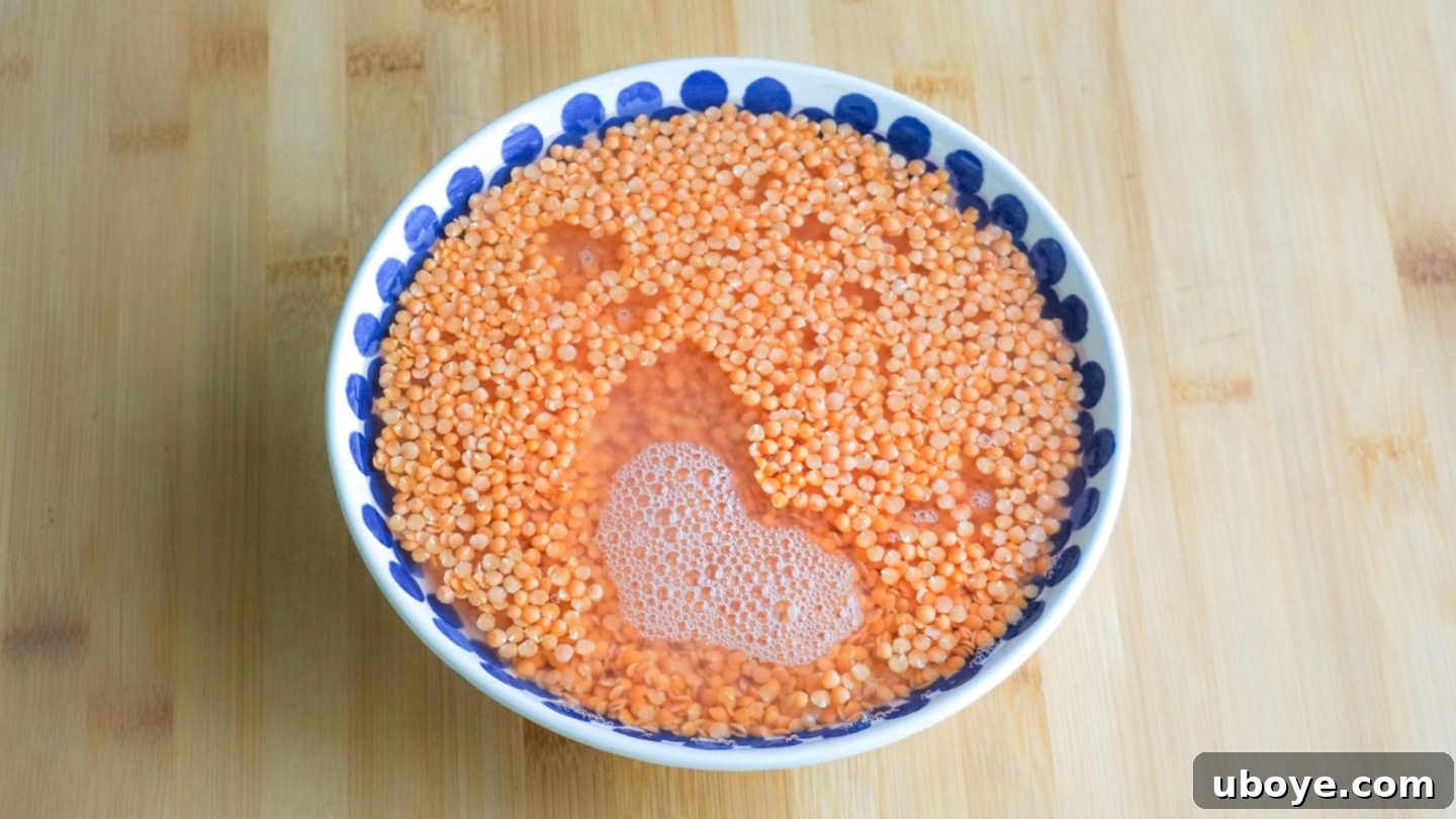 Crimson Lentil Blocks 3 Red lentils soaking in a clear bowl of water, with a small heart shape visible on the surface.