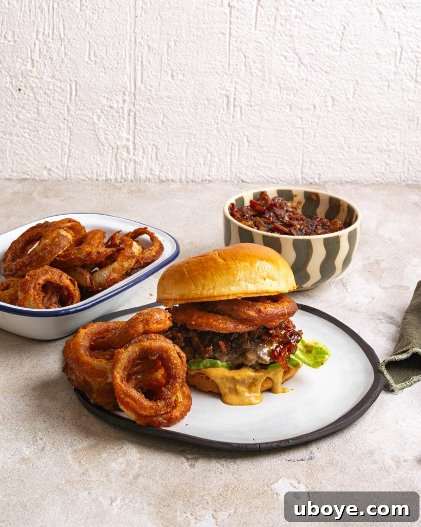 Crispy Onion Ring Burger 2 A perfectly assembled gourmet burger with crispy onion rings and a side of extra rings.