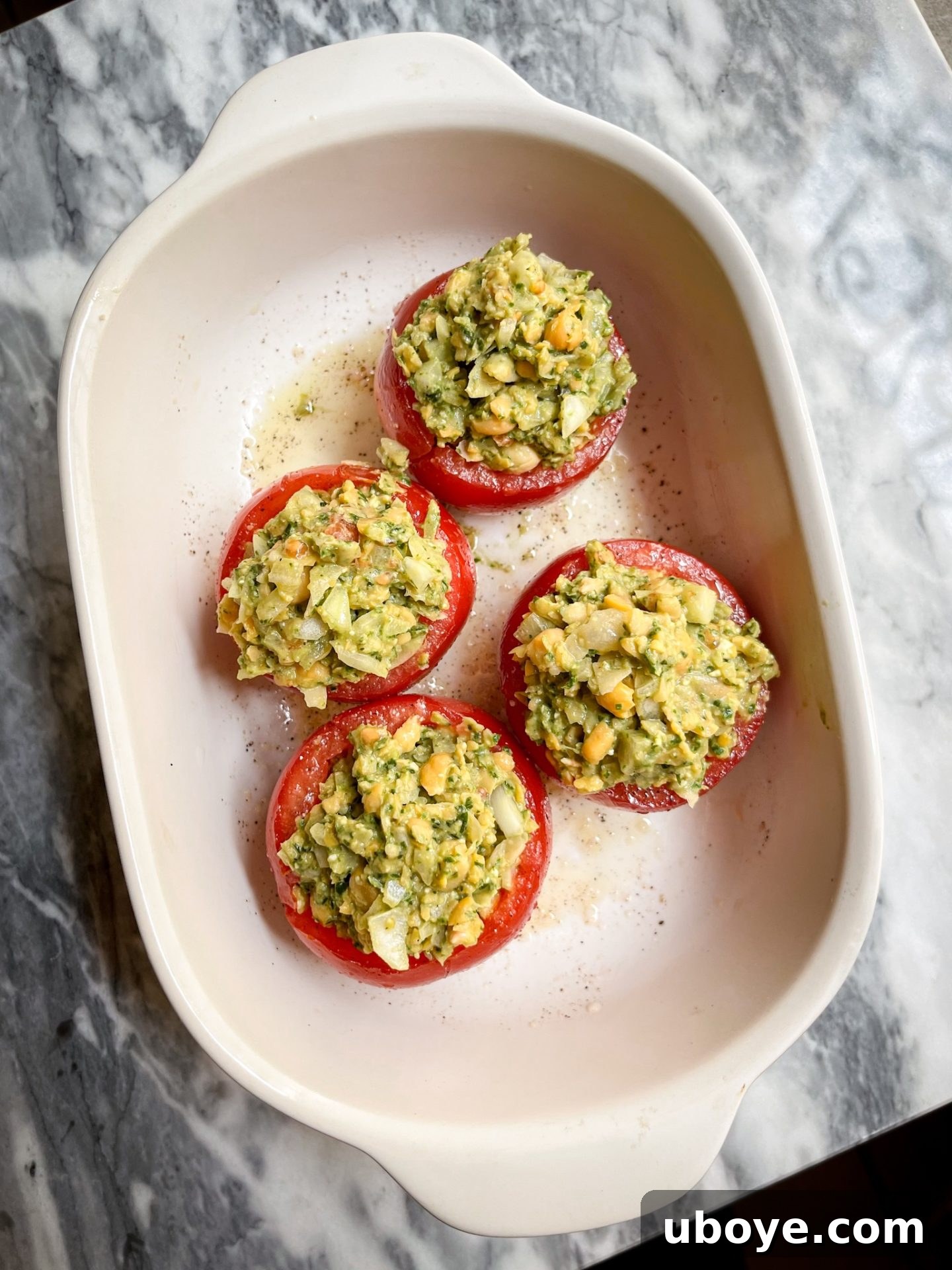 Pesto-Packed Tomato Delights 6 Mashed chickpea and pesto mixture being gently spooned into hollowed tomatoes.