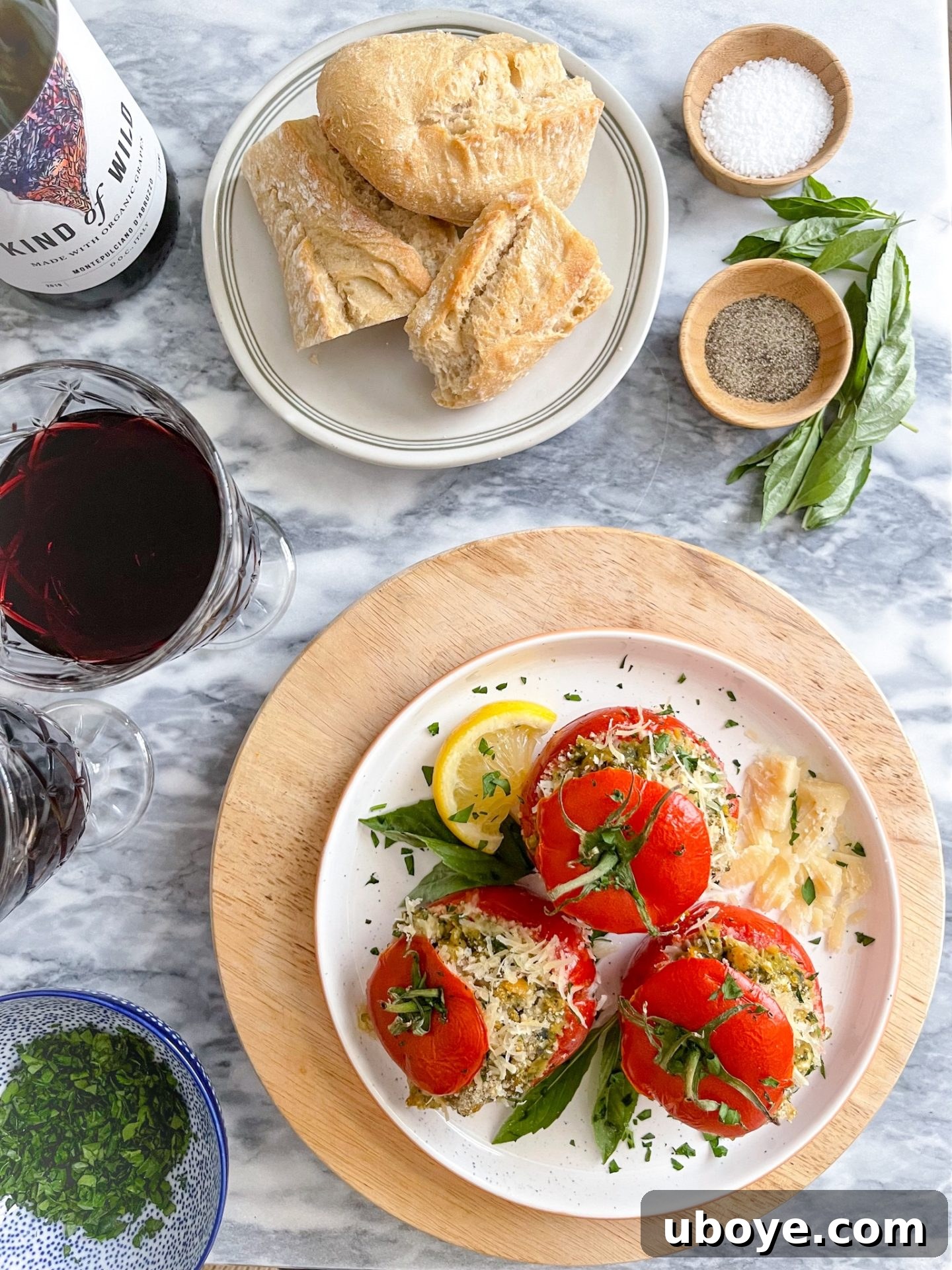 Pesto-Packed Tomato Delights 7 Three pesto stuffed tomatoes on a bed of greens, served on a white plate with a fork.