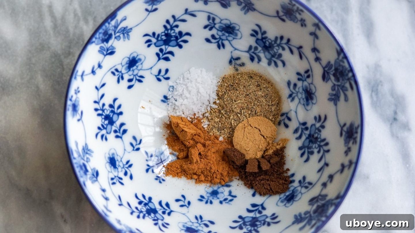 A small blue bowl containing a fragrant mixture of ground cinnamon, cardamom, allspice, ground ginger, and sea salt, ready to be incorporated into the chai spice blend for the French toast.