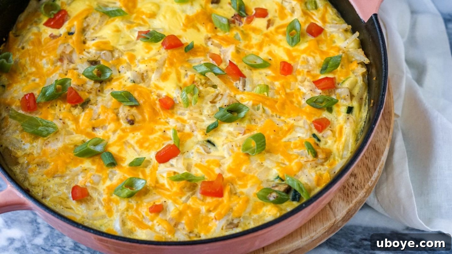 Vibrant vegetables, hash browns, and vegan cheese simmering together in a cast iron skillet, ready for the vegan egg mixture.