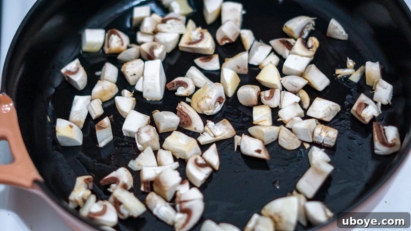 Mushrooms sautéing in a cast iron skillet, developing a golden-brown color for enhanced flavor in the hash brown skillet.