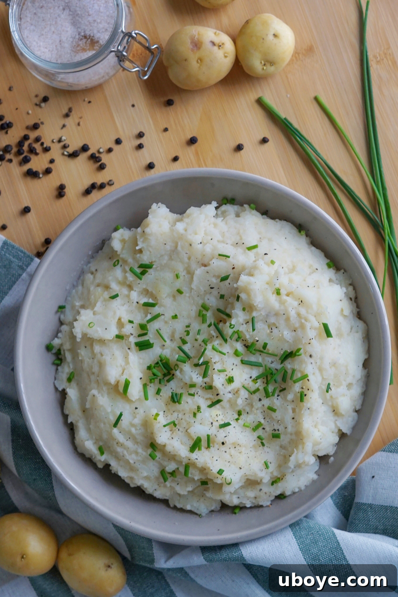 A close-up shot of freshly made creamy cauliflower mashed potatoes garnished with chopped chives in a rustic bowl.